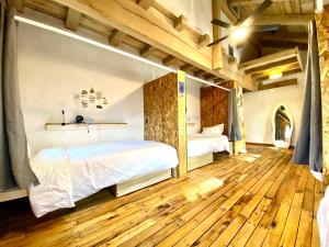 a bedroom with a bed and a wooden floor at The Arete Hostel and Suites in Summersville