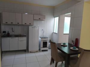 cocina con mesa, nevera, mesa y sillas en Apartamento 303 Encantador, en Vitória da Conquista