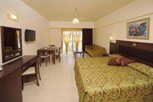 アヤナパにあるEuronapa Hotel Apartmentsのベッドとダイニングルームが備わるホテルルームです。