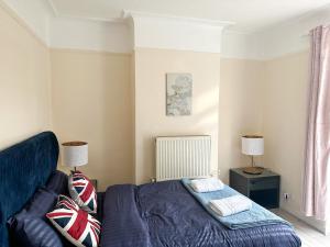 1 dormitorio con 1 cama azul y 2 lámparas en Limehouse Apartment, en Londres