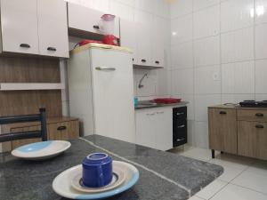 a kitchen with a counter with two plates and a refrigerator at Apartmento 304 Charmoso no Centro de Conquista in Vitória da Conquista