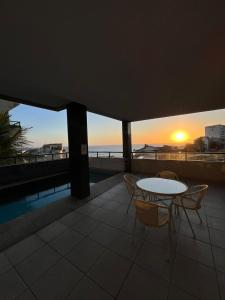 a table and chairs on a balcony with the sunset at Apartamento Solar Rio Vermelho in Salvador