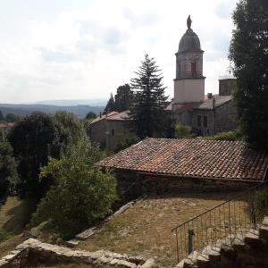 an old building with a clock tower on a hill at Gite de l'Entressac in Pradelles +7 photos