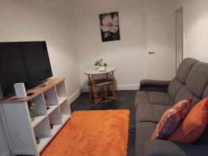 a living room with a couch and a flat screen tv at Luxurious space in Erith