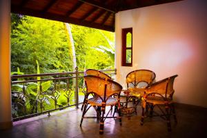 drie stoelen en een tafel op een balkon met een raam bij Binara Home Stay in Polonnaruwa