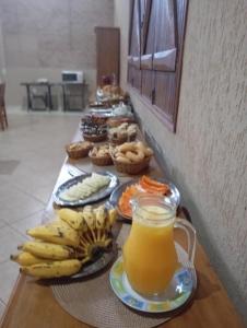 a long table with a bunch of bananas and orange juice at Pousada e Camping Claro Casa de Pedra de Delfinópolis -MG in Delfinópolis