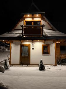 a house with snow on the ground in front of it at Domki na Stoku in Czarna Góra