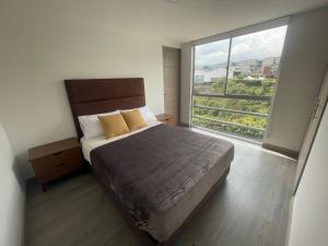 a bedroom with a bed and a large window at Muy Cerca al CC Fundadores, U Autonoma & El Centro in Manizales
