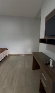 a living room with a tv and a wooden floor at Hotel Helena Palace in Bonfinópolis