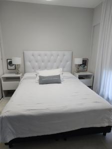 a bedroom with a large white bed with a large headboard at Departamento Margui in San Pedro