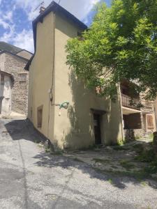 a white building with a tree next to it at Studio idéal court séjour in Porté-Puymorens