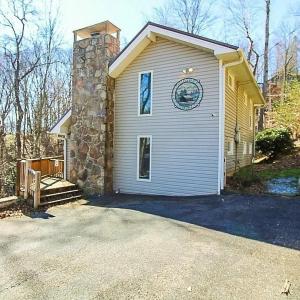 a white house with a stone chimney on it at Whispering Bears Chalet in Gatlinburg