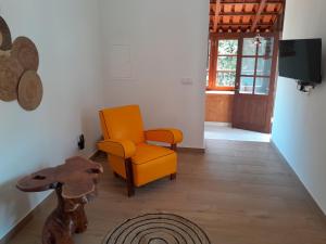 a living room with an orange chair and a table at Kasa Wahnon in Pombas