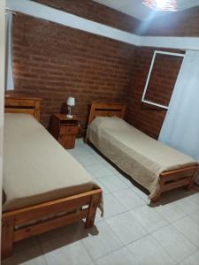 two beds in a room with a brick wall at Cabaña El Chaparral Villa Dolores, Traslasierra 4 in Villa Dolores