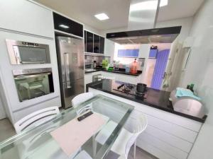 a kitchen with a glass table and white chairs at Casa Enseada Guarujá in Guarujá