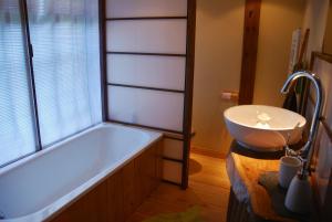 a bathroom with a tub and a sink at Minshuku Chambres d'hôtes japonaises in Thiers