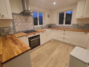 eine Küche mit weißen Schränken und einer Holzarbeitsplatte in der Unterkunft Trillis Cottage in Sapperton + 10 Fotos