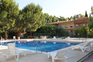una piscina con sillas blancas junto a un edificio en Hostal Tivissa en Tivissa