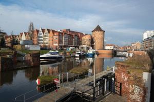 een rivier met boten aangemeerd in een stad met gebouwen bij Szopy 2 in Gdańsk