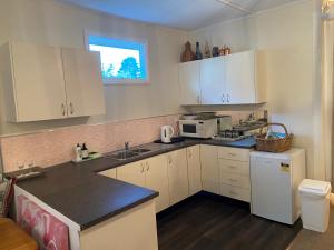 eine Küche mit weißen Schränken und einer Spüle und einer Mikrowelle in der Unterkunft Katoomba Cosy Cottage- entire 65sqm cottage in Katoomba