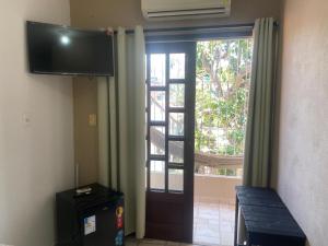 a room with a door with a television and a window at Casa de Japaratinga in Japaratinga