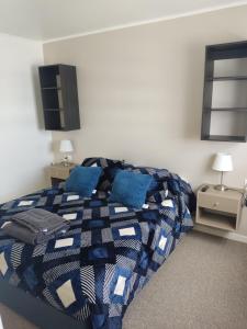 a bedroom with a bed with blue pillows at cabañas los flamencos A in Punta Arenas