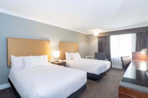 a hotel room with two beds and a television at Sandman Hotel Vernon in Vernon