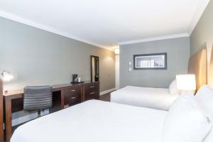 a hotel room with two beds and a desk at Sandman Hotel Vernon in Vernon