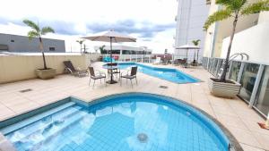 a swimming pool with a table and chairs next to a building at 3 bedrooms with heated pool Temporada Brasilia in Brasilia