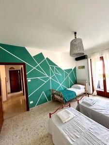 a room with two beds and a green wall at casa al mare per famiglie 2 in Minturno