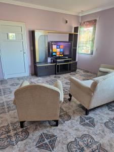 a living room with two chairs and a television at Departamento Emanuel in Comodoro Rivadavia