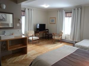 1 dormitorio con cama, escritorio y lavamanos en Auberge la maison sous les pins, en Saint-Joseph-de-la-Rive