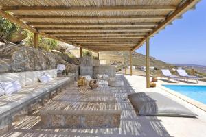 a patio with a couch and a fountain next to a pool at Villa Ananda Mykonianvilla in Panormos Mykonos