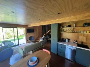 a kitchen and living room with a table in a house at Little Sister - Little Bay, Coromandel in Tuateawa