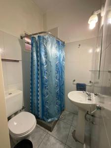 een badkamer met een toilet en een blauw douchegordijn bij Atalaya in Puerto Madryn