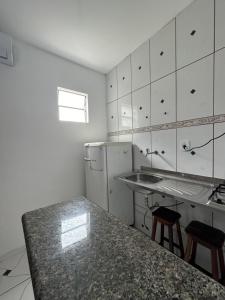 a kitchen with a sink and a refrigerator and a counter at Kitnet Praia Grande in Arraial do Cabo +9 photos