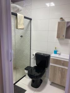 e bagno con doccia e servizi igienici neri. di Casa - Chalé Recanto da Natureza a Imbituba