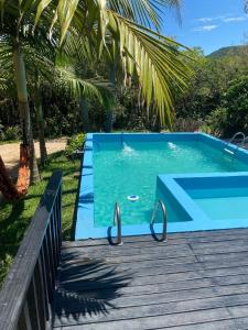 una piscina blu accanto a una terrazza in legno di Casa - Chalé Recanto da Natureza a Imbituba