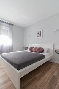a white bedroom with a large bed with brown pillows at Apartments by the sea Nin, Zadar - 23664 in Nin