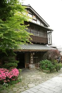 an asian building with pink flowers in front of it at Magome Chaya in Nakatsugawa