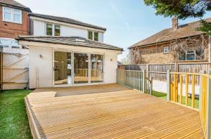 a wooden deck in the backyard of a house at Exquisite Home Away From Home in Greenford