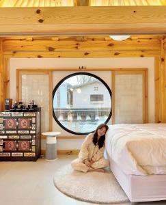 a woman sitting on a rug next to a bed at Hanok Prince in Gyeongju