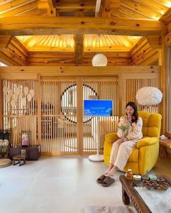 a woman sitting on a yellow couch in a living room at Hanok Prince in Gyeongju +25 photos