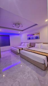 two beds in a room with purple lighting at Lucky Hotel Uông Bí in Uông Bí