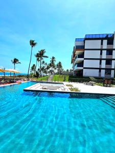 a large swimming pool next to a building with palm trees at Sofisticação e Luxo à Beira-mar no Cais Eco em Muro Alto by HM in Porto De Galinhas