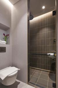 a bathroom with a toilet and a glass shower at Citadines Connect City Centre Singapore in Singapore