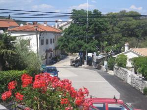 un coche rojo estacionado en una calle con flores rojas en Guesthouse Villa Galovic, en Brseč