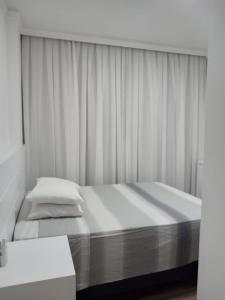 1 dormitorio blanco con 1 cama con cortina en Apartamento 3 suítes a 100m do mar, en Itapema 10 fotos más