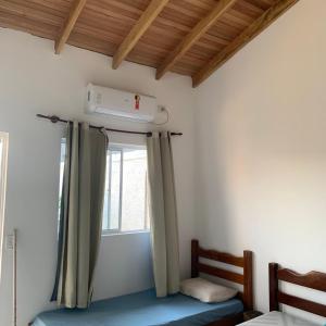 a room with a bed and a window with curtains at Casa Para temporada - casa ARASĒ in Bonito