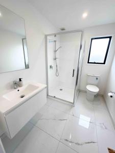 a white bathroom with a shower and a sink at Coastal Charm Escape in Karikari Peninsula +19 photos